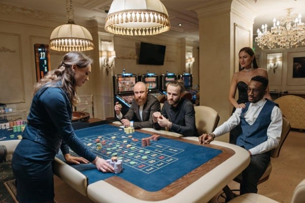 Dealer at live casino roulette table with players and chips